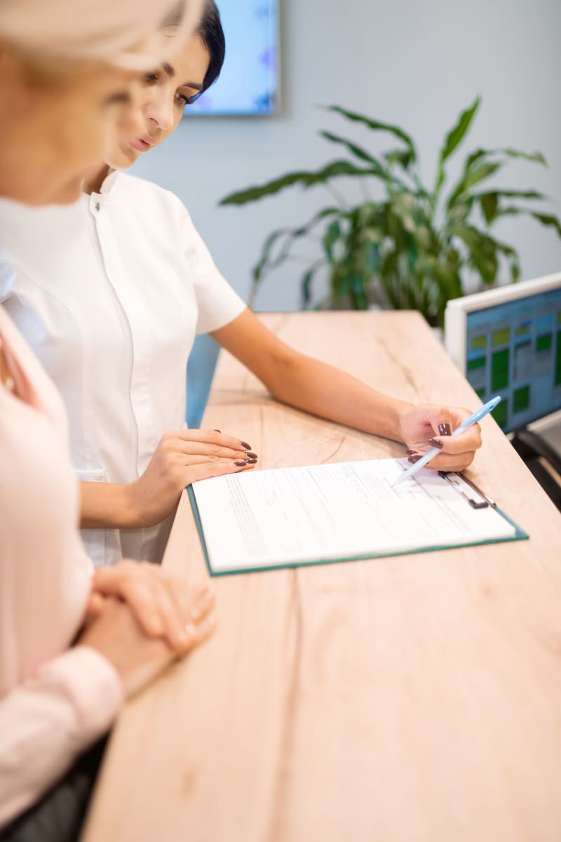 A dental professional is taking a patient through a form in a clipboard. They are standing at a counter.