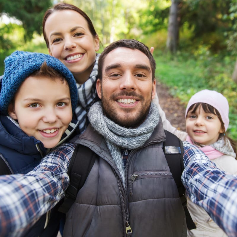 A family of four takes a selfie while on a hiking trip.