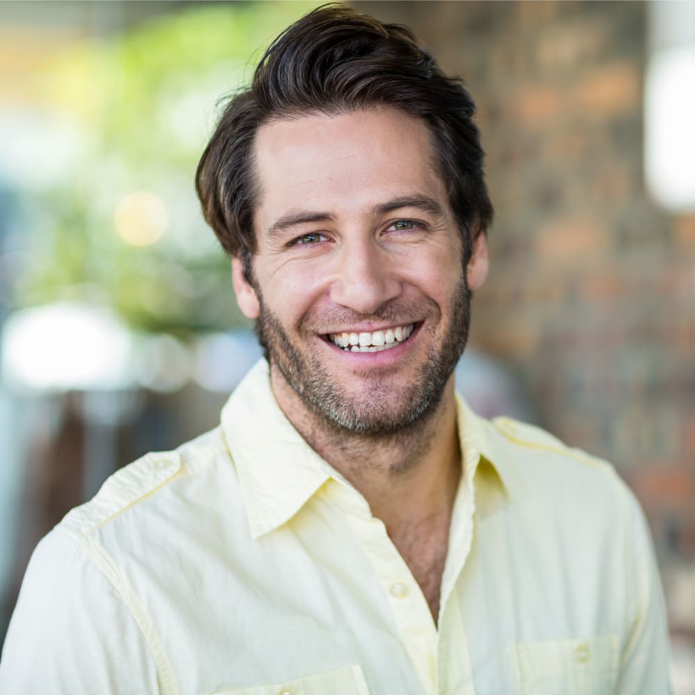 A man in a yellow shirt is smiling at the camera.