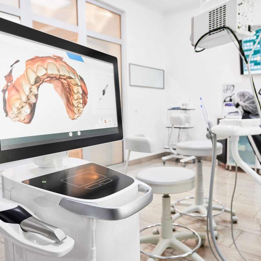 A scan of a patient's teeth is displayed on a screen in a dental treatment room.